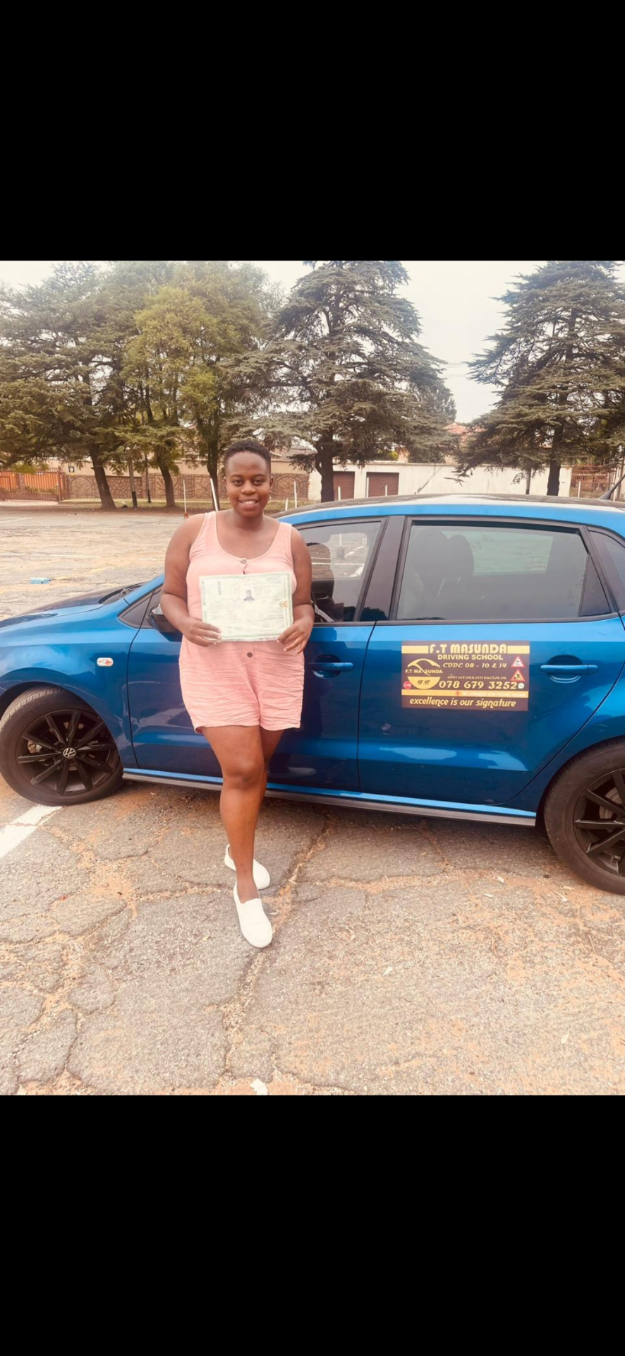 F.T Masunda student with their licence next to the branded training car